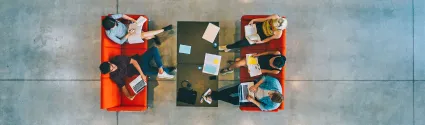 Individuals sitting in lounge chairs with books and laptops.