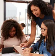 Adult woman instructing teens with mobile device.