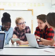 A group of teenagers using laptops.