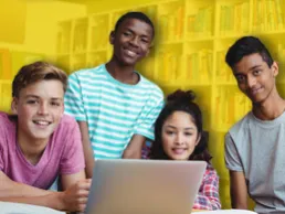 Four teens in a library, looking at a computer screen together