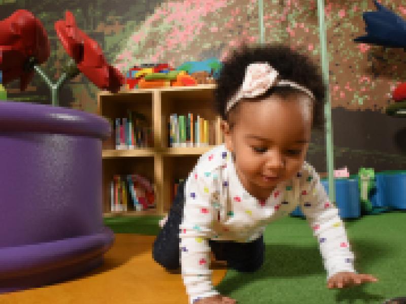 A baby crawling in a Storyville play area.