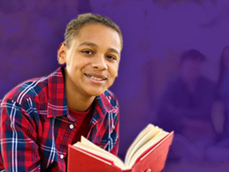 Boy wearing a flannel shirt holding a book