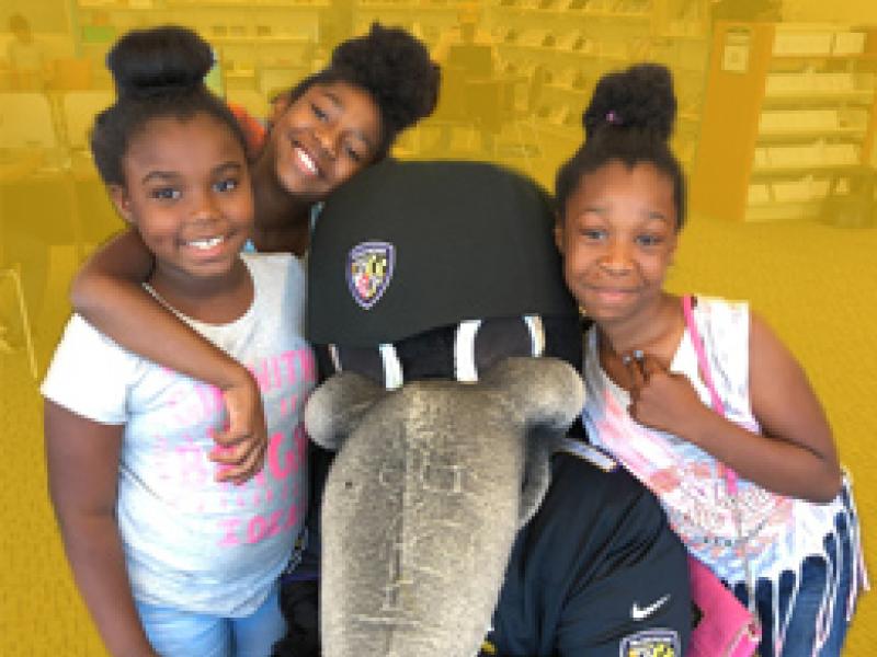 A group of young girls around Baltimore Raven's Mascot, Poe