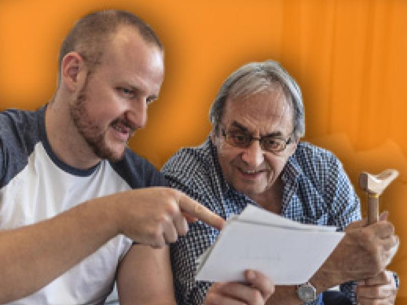 A photo of a elderly male looking at photos with his son