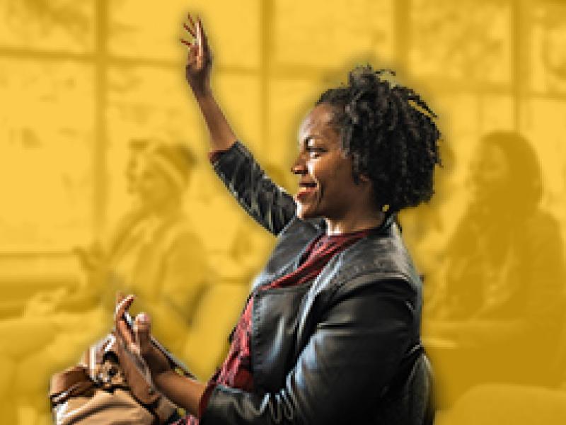 Woman raising her hand to ask a question at a community gathering