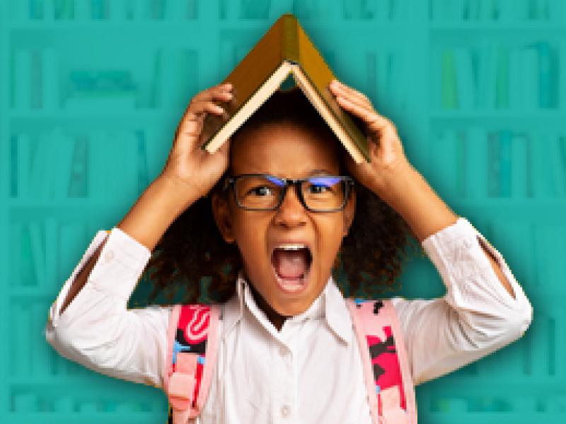 a school aged girl shouting with a book on her head