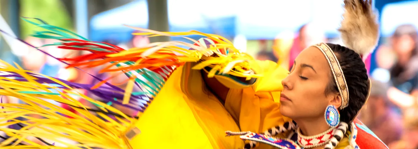 photo of a young native american woman dancing in tribal clothes