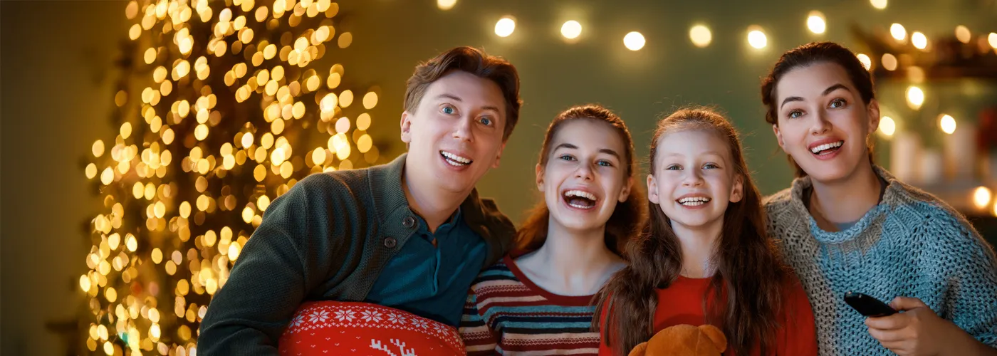 Family watching a movie with holiday lights in the background