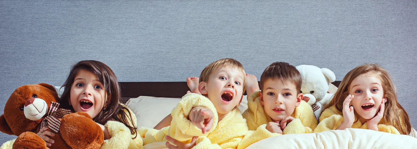 Four children lined up on a bed in their pajamas