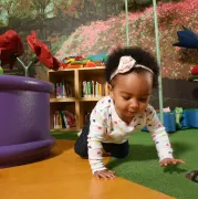 A baby crawling in a Storyville play area.