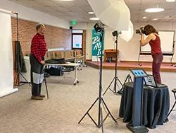 Photo of a woman taking a photo of a man in a plain shirt