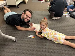 Man and daughter coloring on the carpet