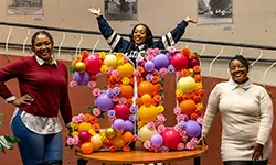 Group of women standing by the number "30" made out of balloons